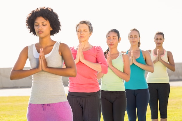 Mujeres deportivas pacíficas que hacen posición de oración en la clase de yoga