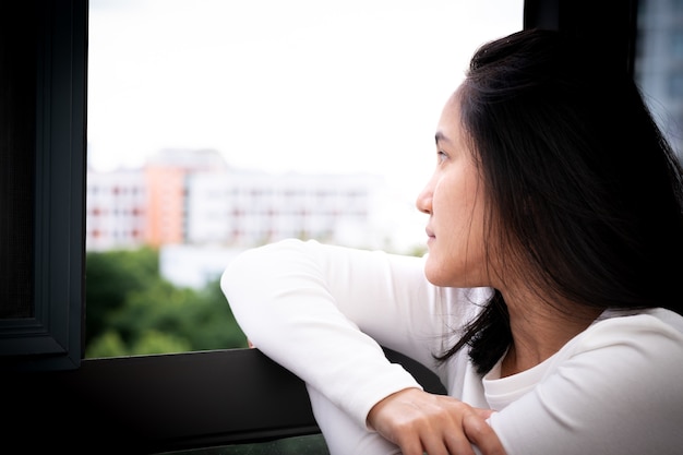 Mujeres deprimidas que se sientan cerca de la ventana, solo, tristeza, concepto emocional