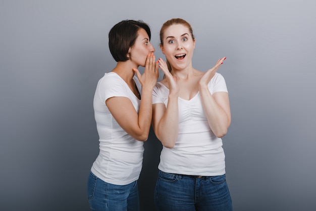 Mujeres diciendo un secreto a su amiga. Maravilla emoción en la cara