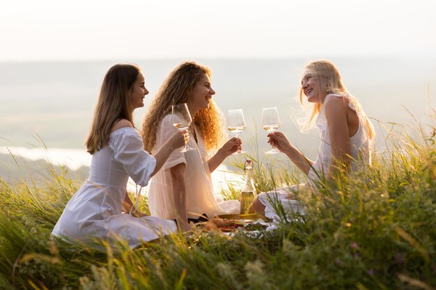 mujeres disfrutando de un picnic de verano al atardecer en la colina