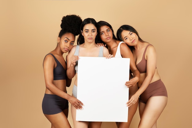 Mujeres diversas en ropa interior sosteniendo un cartel en blanco para el diseño