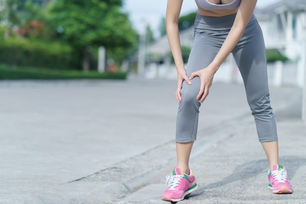 Mujeres con dolor de rodilla. Deporte ejercitando lesiones. Mujer adolorida mientras corre.