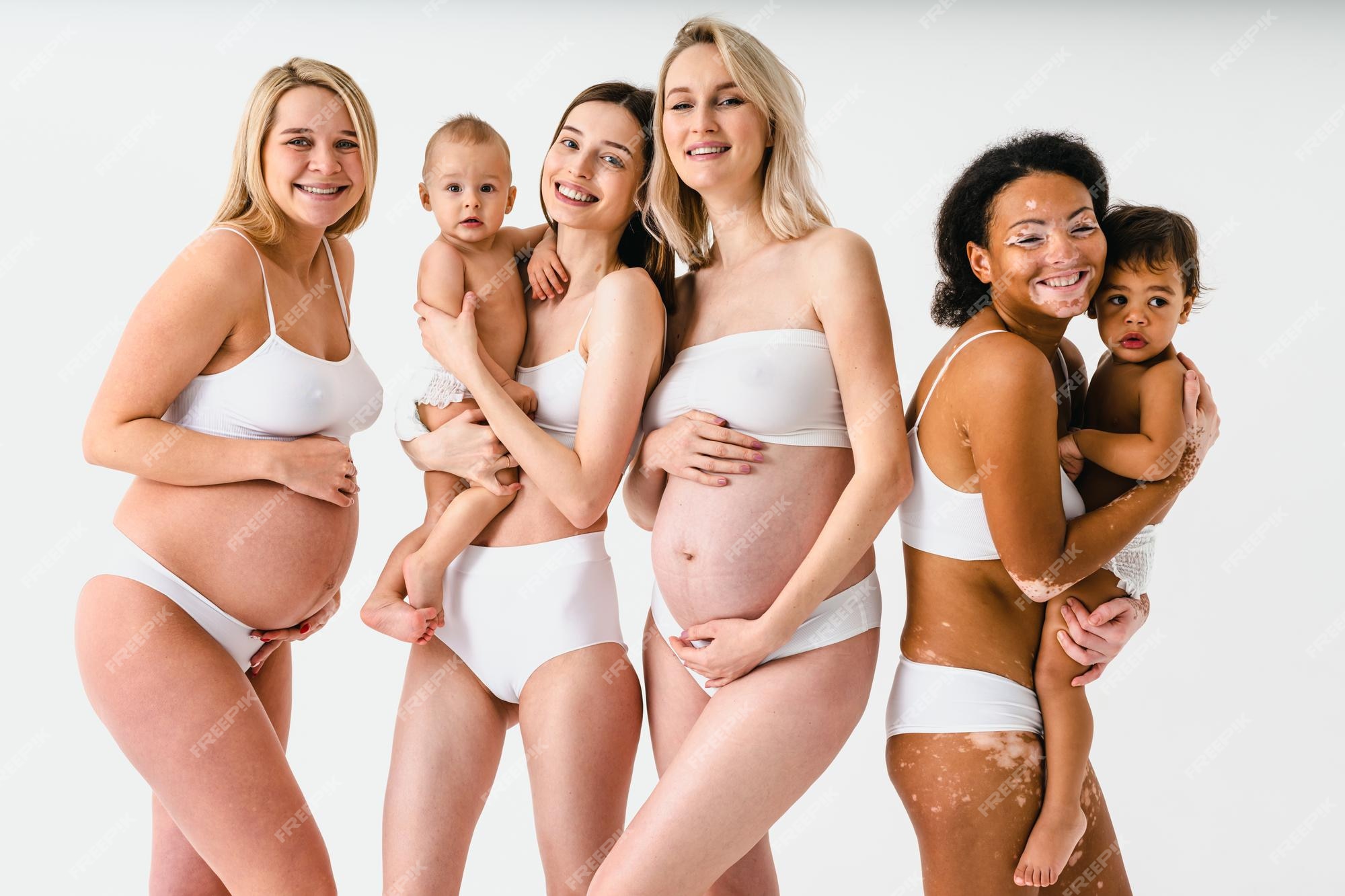 Mujeres embarazadas felices con gran y hermosas madres con bebés en el estudio - grupo multirracial de mujeres embarazadas y madres con niños que usan ropa interior - embarazo, maternidad, personas,
