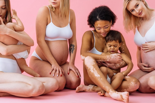 Mujeres embarazadas felices con gran barriga y hermosas madres con bebés en estudio