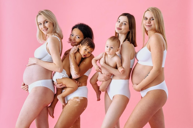 Mujeres embarazadas felices con gran barriga y hermosas madres con bebés en estudio