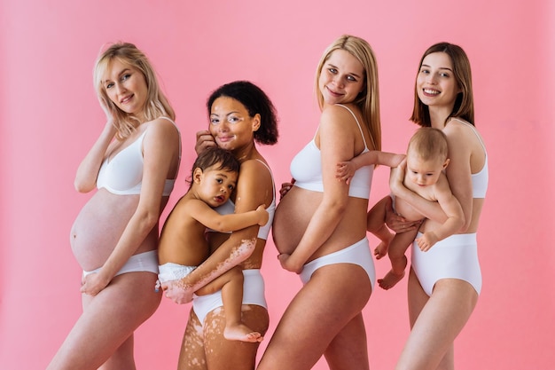 Mujeres embarazadas felices con gran barriga y hermosas madres con bebés en estudio