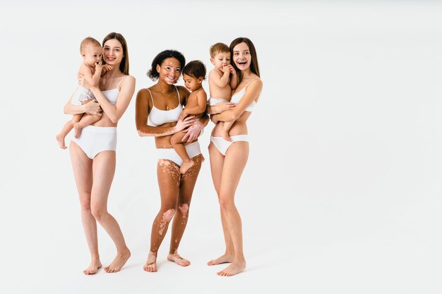 Foto mujeres embarazadas felices con gran barriga y hermosas madres con bebés en estudio