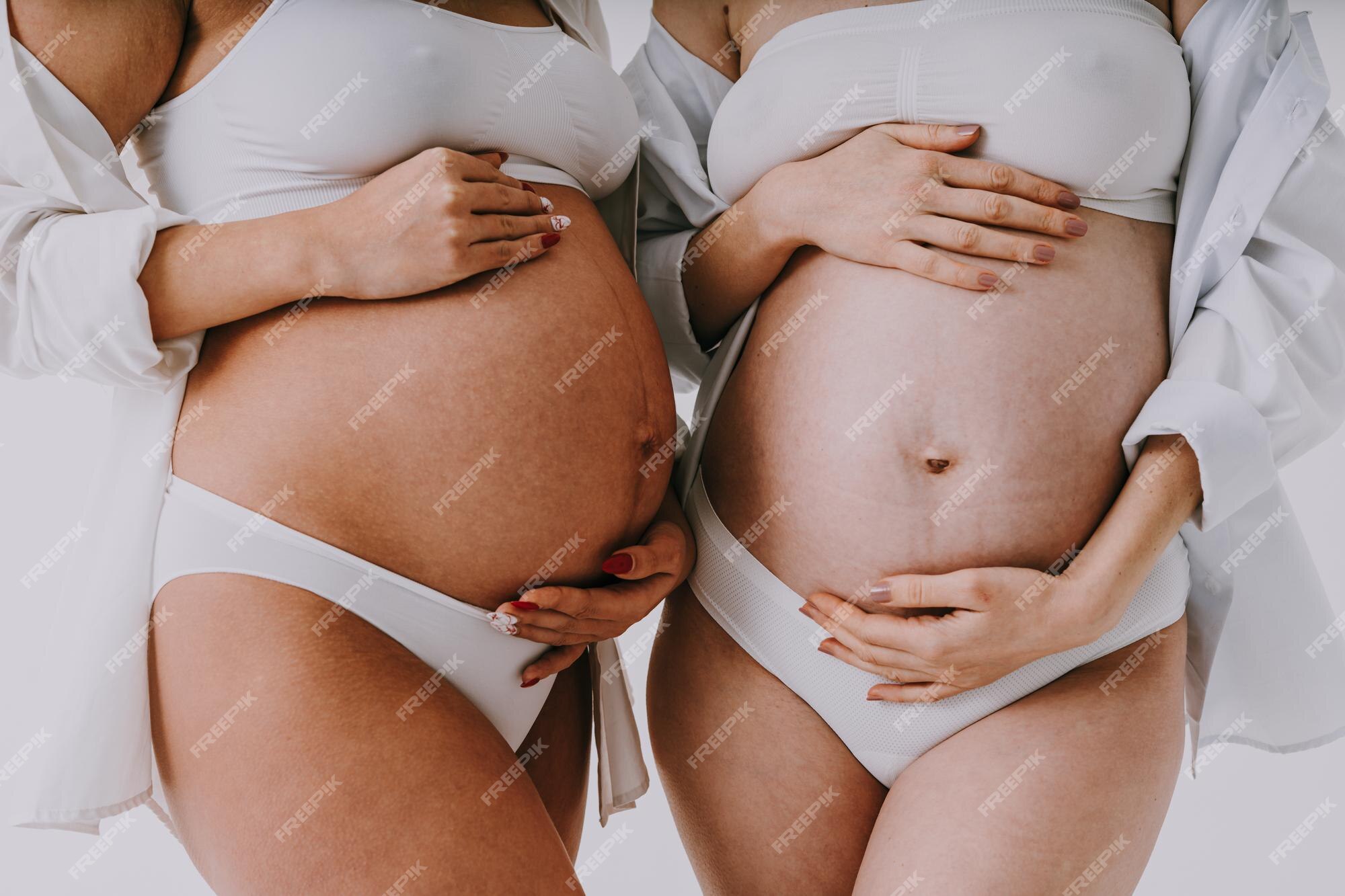 Mujeres embarazadas felices con gran barriga sobre fondo de color - mujeres jóvenes que usan ropa interior esperando un bebé - embarazo, maternidad, personas concepto de expectativa | Foto Premium