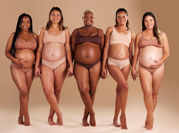 Mujeres embarazadas o retrato de diversidad con estómago en el fondo del estudio en amor corporal bebé o apoyo comunitario Sonrisa feliz o amigos del embarazo en ropa interior para el crecimiento de la barriga o el empoderamiento de las madres