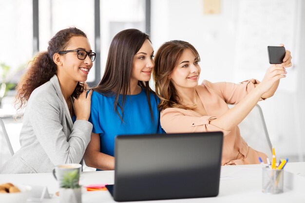 Foto mujeres empresarias felices tomando selfie en la oficina