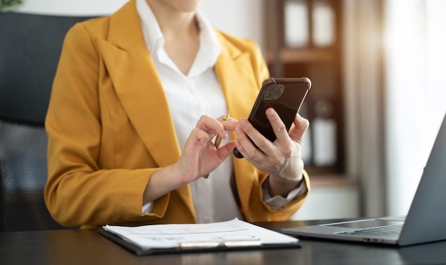 Mujeres empresarias que trabajan con teléfonos inteligentes, computadoras portátiles y tabletas digitales en la oficina