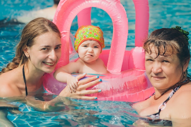 Las mujeres enseñan al bebé a nadar. Niña con juguetes inflables para la piscina. enseñanza de natación, accesorios, ocio
