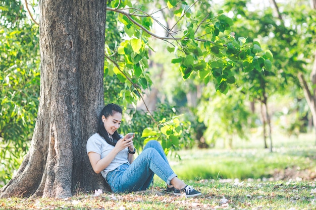 Las mujeres escuchan música y se relajan bajo los árboles.