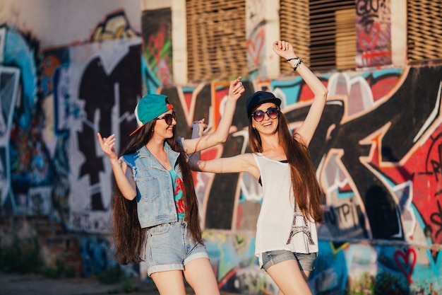 Mujeres con estilo alegres en la pared de graffiti