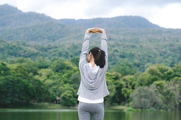 Las mujeres estiran los brazos y se retuercen para relajar los músculos. Mira a lo lejos con la naturaleza en el horizonte. En medio de la hermosa naturaleza.