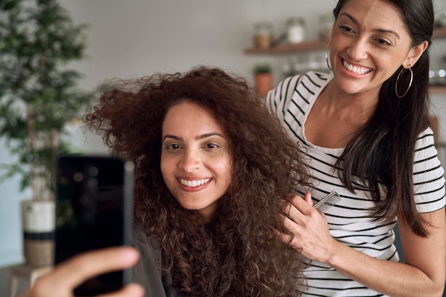 Mujeres felices tomando selfies mientras se peinan el cabello