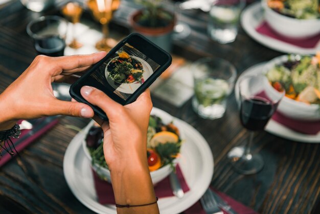 Mujeres fotografiando ensalada con teléfono inteligente en un restaurante vegetariano