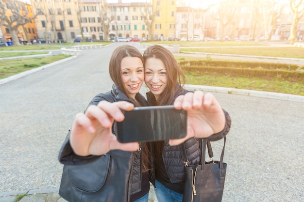 Mujeres gemelas tomando un selfie en la ciudad.