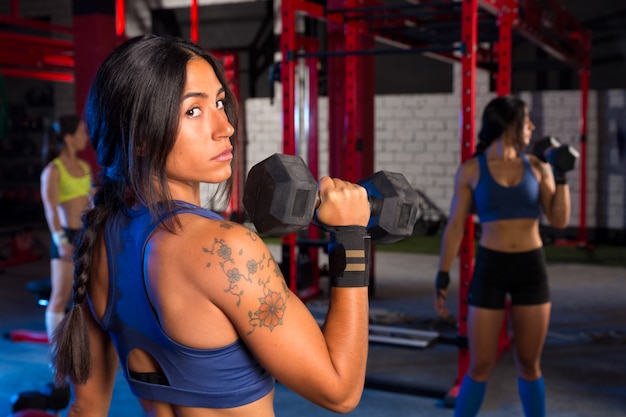 Mujeres de gimnasio con entrenamiento de barra hexagonal