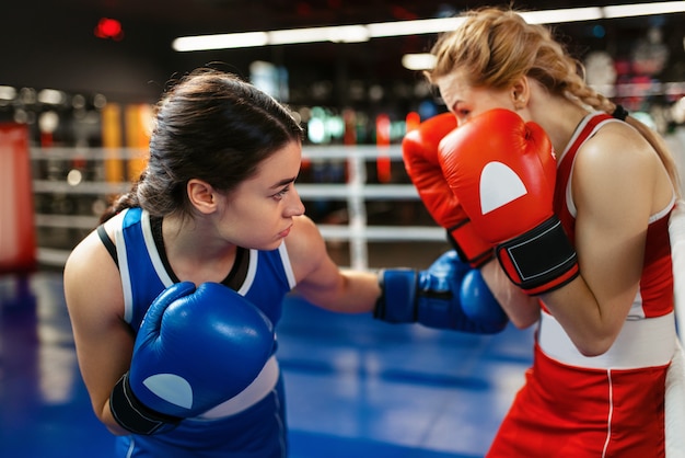 Mujeres en guantes rojos y azules de boxeo en el ring