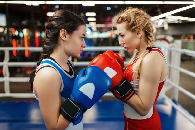 Mujeres en guantes rojos y azules de boxeo en el ring