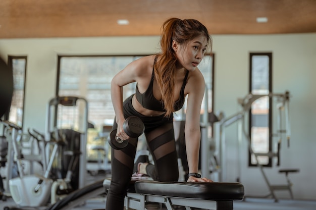 Las mujeres hacen ejercicio con pesas en el gimnasio interior para una buena salud al atardecer en la vista lateral