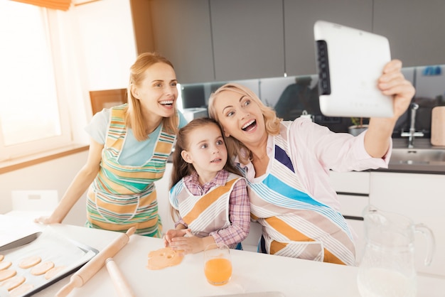 Las mujeres hacen selfies con una chica en la cocina.