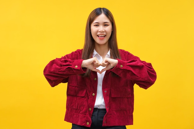 Mujeres haciendo gestos en forma de corazón con ambas manos y felicidad sonriendo en un fondo amarillo aislado