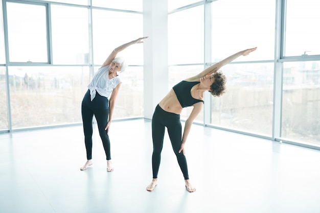 Mujeres haciendo yoga junto a una ventana grande