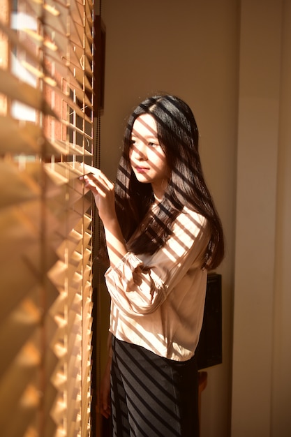 Mujeres hermosas de la belleza que se colocan en la ventana