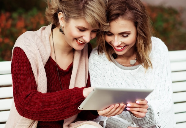 Mujeres hermosas chicas usando tableta al aire libre