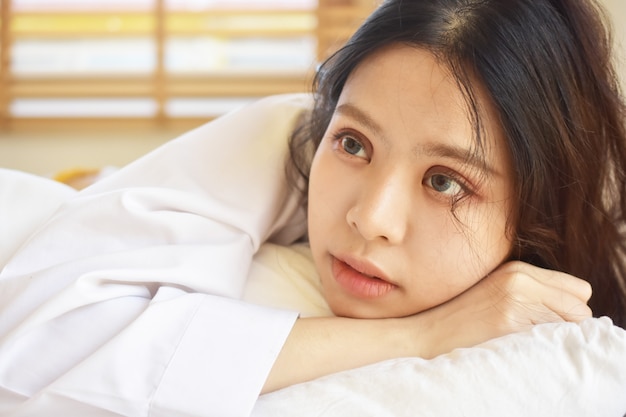 Mujeres hermosas se están despertando y en una cama blanca por la mañana.