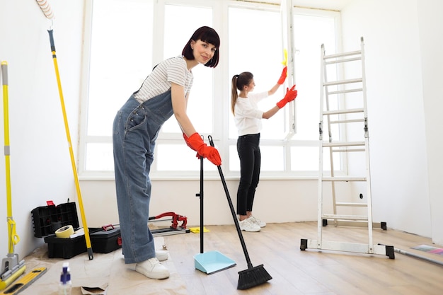 Mujeres hermosas jóvenes limpiando un nuevo apartamento después de la renovación