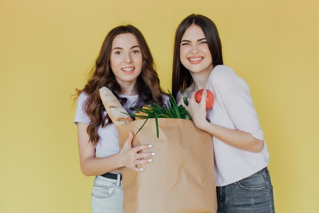 Mujeres hermosas jóvenes sosteniendo una bolsa de papel para llevar de la entrega sobre fondo amarillo estresada