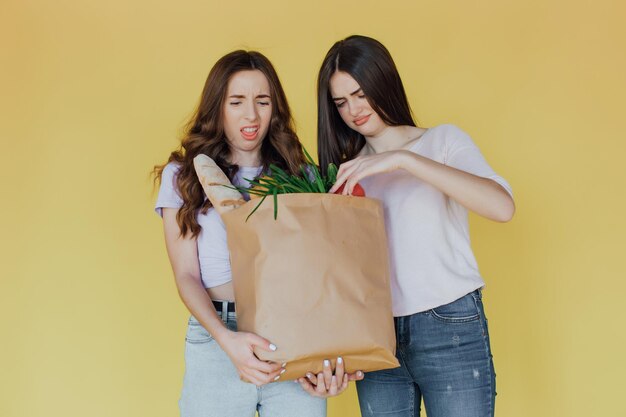 Mujeres hermosas jóvenes sosteniendo una bolsa de papel para llevar de la entrega sobre fondo amarillo estresada