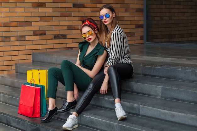 Mujeres hermosas de moda posando en el fondo de la ciudad con bolsas de la compra.