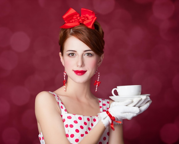 Mujeres hermosas pelirrojas con taza de té. Foto de estilo retro con bokeh de fondo.