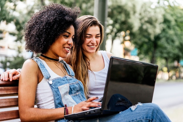 Mujeres hermosas usando una computadora portátil en la calle. Concepto de juventud.