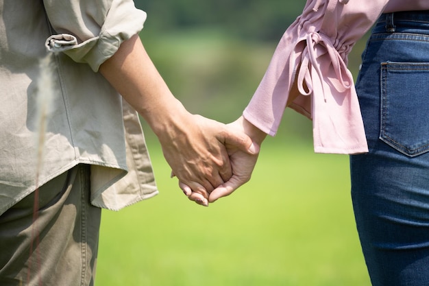 Mujeres y hombres cogidos de la mano caminando sobre el césped natural