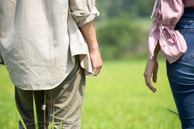 Mujeres y hombres cogidos de la mano caminando sobre el césped natural