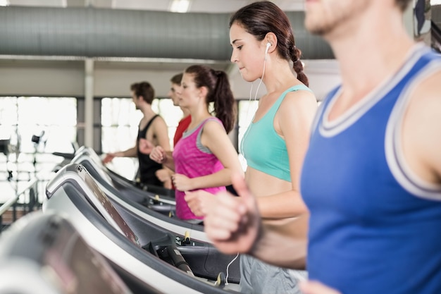 Mujeres y hombres corriendo en una cinta en el gimnasio.