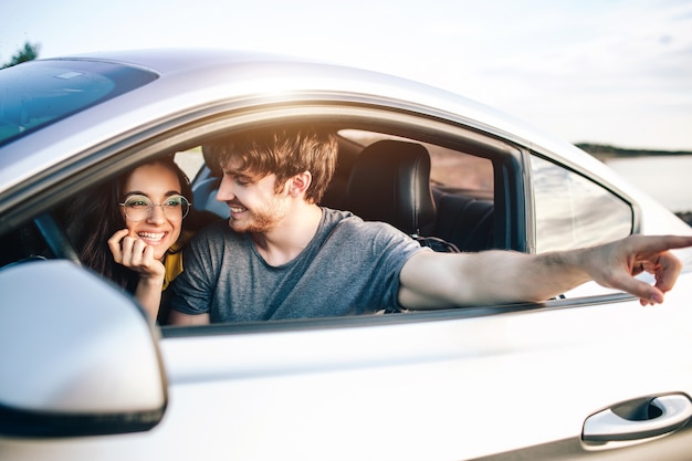 Mujeres y hombres jóvenes de moda que viajan en coche. Feliz pareja relajada en viaje de vacaciones de verano.