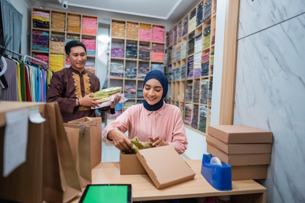 Mujeres y hombres musulmanes preparando el paquete de entrega en el servicio de envío de dropshipping de comercio electrónico de la tienda