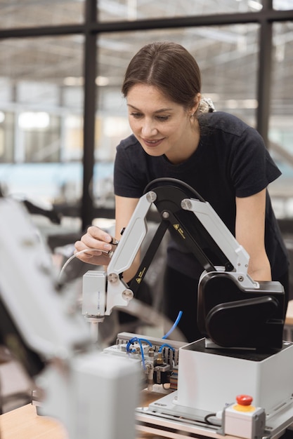 Mujeres ingenieras aprenden educación en el programa de Robótica Industrial con un modelo de simulación de brazo robótico en el aula de laboratorio de ingeniería de la universidad