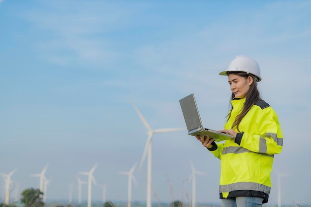 Mujeres ingenieras trabajando y sosteniendo el informe en la estación generadora de energía de la granja de turbinas eólicas en la gente de mountainThailand