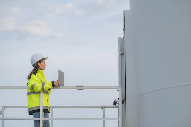 Mujeres ingenieras trabajando y sosteniendo el informe en la estación generadora de energía de la granja de turbinas eólicas en la gente de mountainThailand