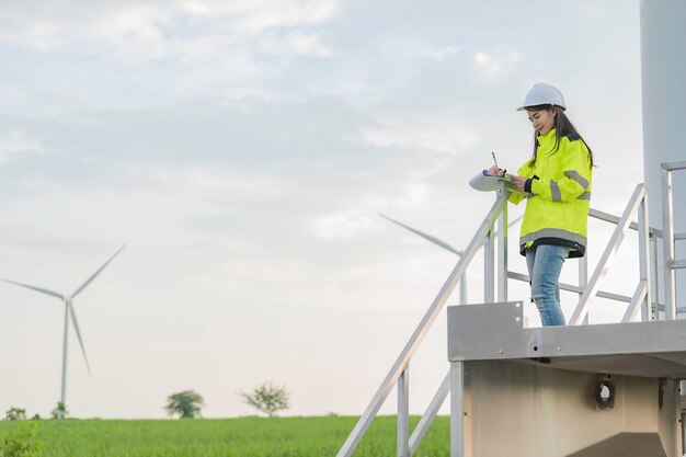 Mujeres ingenieras trabajando y sosteniendo el informe en la estación generadora de energía de la granja de turbinas eólicas en la gente de mountainThailand