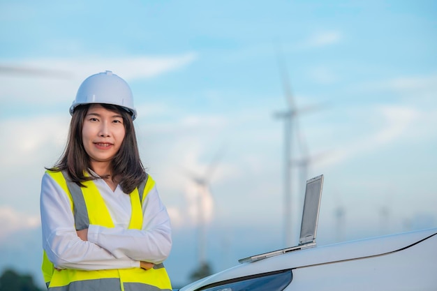 Mujeres ingenieras trabajando y sosteniendo el informe en la estación generadora de energía de la granja de turbinas eólicas en la gente de mountainThailand