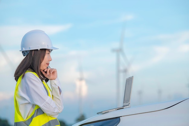 Mujeres ingenieras trabajando y sosteniendo el informe en la estación generadora de energía de la granja de turbinas eólicas en la gente de mountainThailand