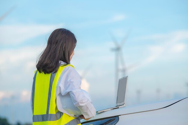 Mujeres ingenieras trabajando y sosteniendo el informe en la estación generadora de energía de la granja de turbinas eólicas en la gente de mountainThailand